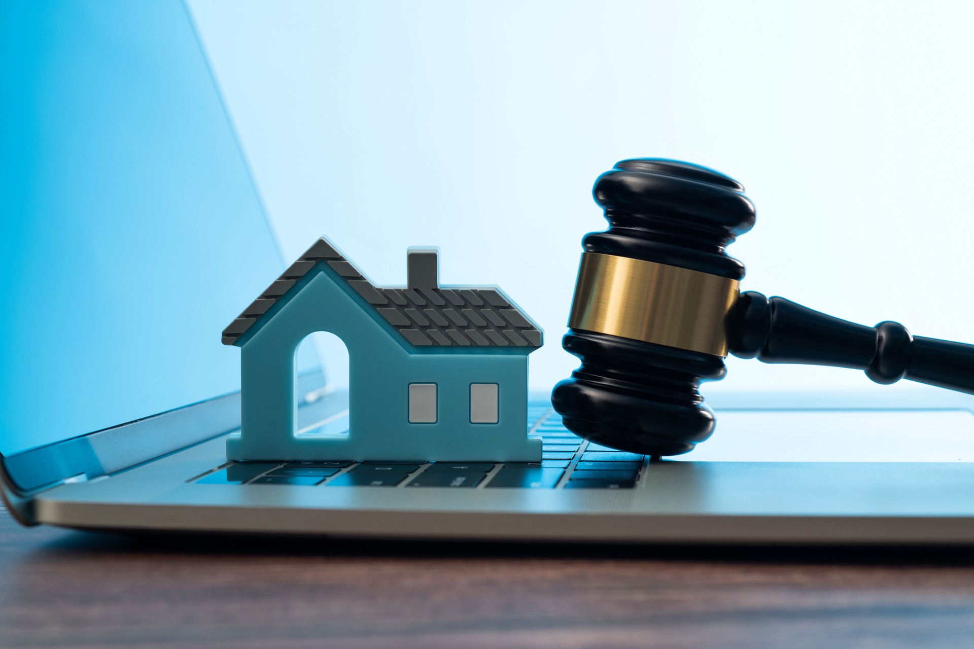 Gavel and model house on laptop keyboard